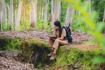 Biologist or botanist recording information about tropical plants in forest. The concept of hiking to study and research botanical gardens by searching for information.