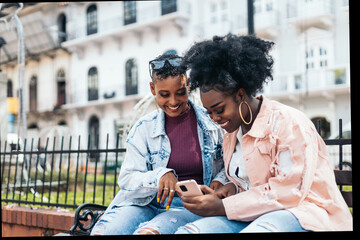 black women friends using smartphone having fun in the city