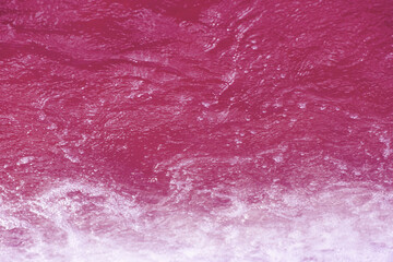 Pink water splashes on the surface ripple blur. Defocus blurred transparent red colored clear calm...