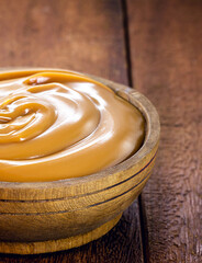 pot of vegan dulce de leche or homemade caramel on rustic wooden background, typical Brazilian sweet