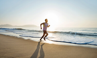 Young man running along beach  in the morning - obrazy, fototapety, plakaty