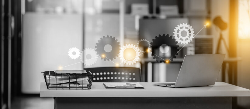 Nobody, no people, modern, monochrome office setup with a laptop on a desk. Gears and cogs appear to symbolize workflow or automation concepts.