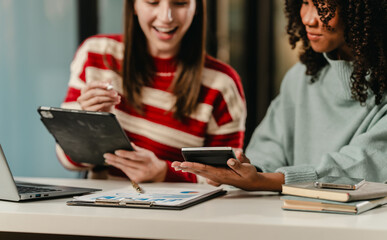 Caucasian and an African American student smiling and looking at a tablet, possibly collaborating on a university project.
