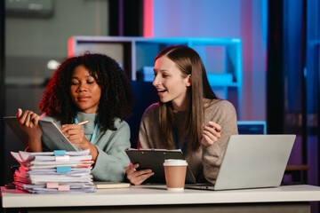 African American trainee with an afro and a Caucasian colleague working together in an office, possibly during overtime.