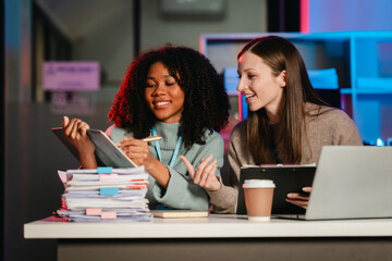 African American trainee with an afro and a Caucasian colleague working together in an office, possibly during overtime.