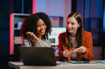African American business worker with an afro presenting a UX,UI design on a clipboard to a Caucasian colleague in an office setting.