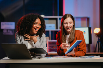 African American business worker with an afro presenting a UX,UI design on a clipboard to a Caucasian colleague in an office setting.