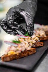 Professional chef cooking forshmak of herring with black bread in restaurant kitchen