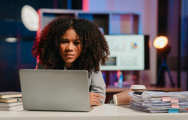 bored African American office worker with an afro, resting her cheek on her hand while looking at a...