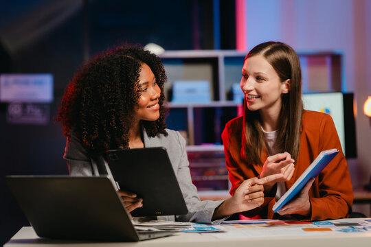 African American business worker with an afro presenting a UX,UI design on a clipboard to a Caucasian colleague in an office setting.