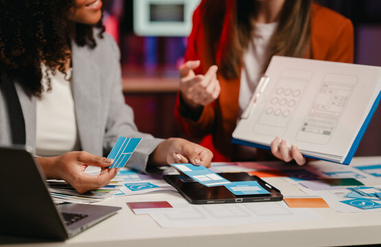 African American business worker with an afro presenting a UX,UI design on a clipboard to a Caucasian colleague in an office setting.