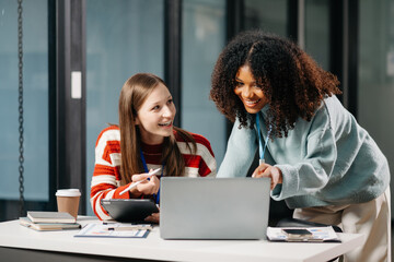 Businesswomen work and discuss their business plans. African women employee explains and shows her colleague the results paper in modern office.