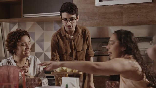 Young man serving his guests, in the kitchen of his home. Cinematic 4k.