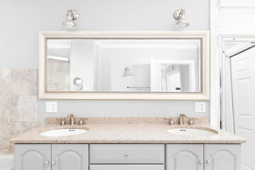 A bathroom detail with a grey vanity cabinet, brown quartz countertop, and lights mounted above the...