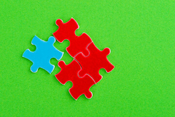 Three red and one blue puzzle pieces on green background