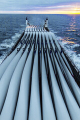 Transportation of blades for wind turbines on a cargo ship across the ocean at sunset. - obrazy, fototapety, plakaty