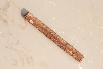 A small piece of rusted iron rod or sariya on cemented floor under sunlight