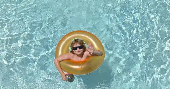 Happy kid playing with colorful swim ring in swimming pool on summer day. Summer Child and water toys. Children play in summer tropical resort. Family beach summer vacation.