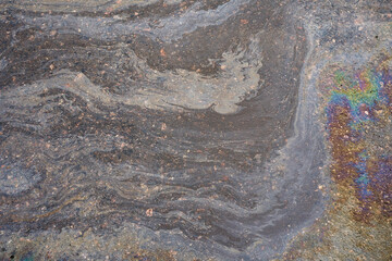 Oily film of rainbow oil or gasoline spill on the surface of a puddle, top view