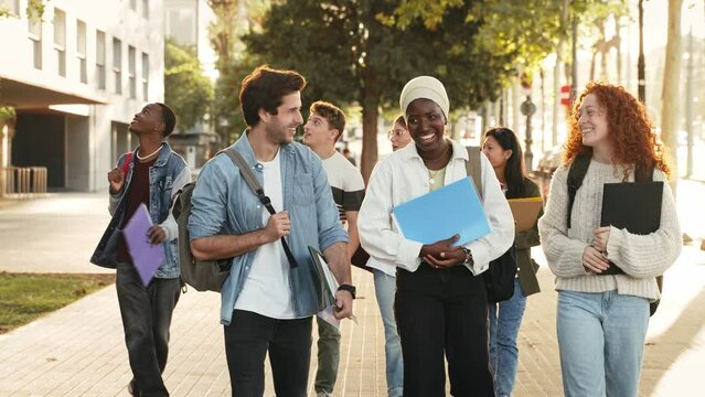 Group of University Students Walking after classes Holding Books, talking and Laughing - Cultural diversity in education