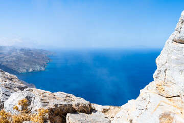 Natural window opening into the sea of Folegandros Island.  Photo taken from the top of a cliff with some fog. Cyclades of Greece.