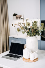 Home Office Setup with Laptop and Cozy Kitchen Decor. A chic home office setup featuring an open laptop on a marble countertop, complemented by a warm kitchen ambiance and stylish decor.