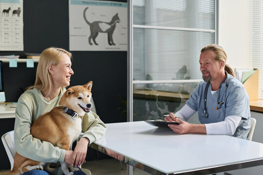 Veterinarian and dog owner having positive conversation during checkout in clinic