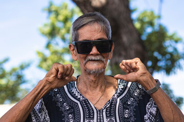 A cool hippie granddad pointing to the camera pointing to himself with both thumbs with confidence....