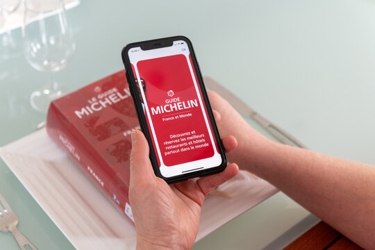 Paris, France - December 20, 2023 - Red Michelin guide book and smartphone application, which reviews restaurants.