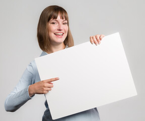Young woman with is pointing to an empty advertising board in her hand