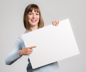 Young woman with is pointing to an empty advertising board in her hand