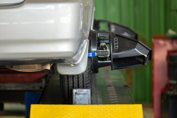 Mechanic tuning aligner for wheel alignment in garage closeup. Professional car maintenance in...