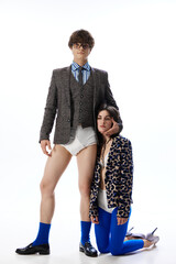 Unhealthy relationship. One of partner mentally tired stands on knees next to guy in costume but without pants, in underwear. Concept of odd romance, bizarre love, Valentine's Day, fashion, glamour.