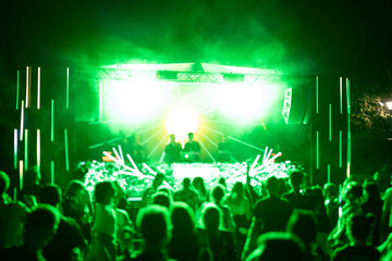 Crowd of people attending a musical performance. Bright neon green light rays coming from the stage