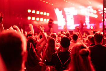 Crowd of people attending a musical performance. Bright red light coming from the stage