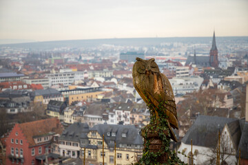an owl carved out of wood with a city in the background