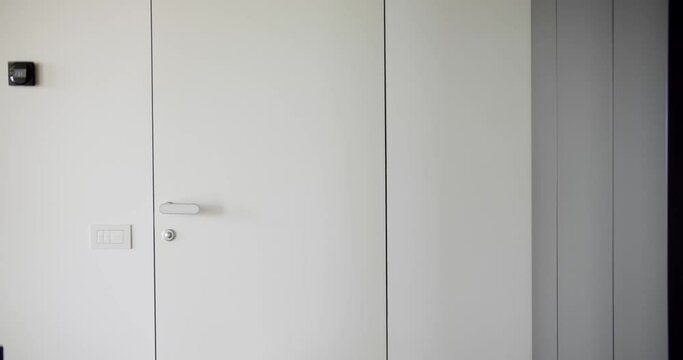 Detail in home interior, room door in white color with handle and lock. Frameless door in house with modern design. Minimalist style in apartment