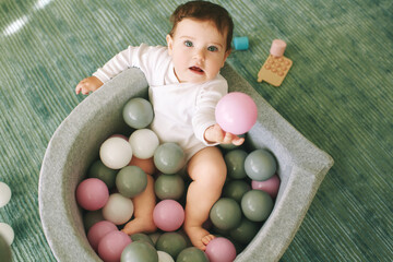 Adorable baby girl playing with mini ball pit, fun and activities for little kids