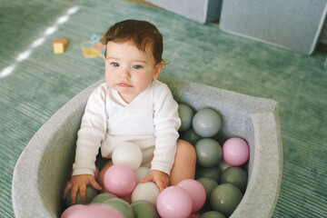 Adorable baby girl playing with mini ball pit, fun and activities for little kids
