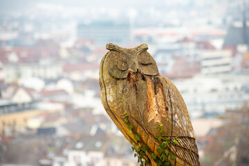 an owl carved out of wood with a city in the background
