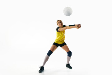 Dynamic competitive young woman, volleyball player in motion during game, hitting ball isolated over white background. Concept of sport, competition, active and healthy lifestyle, hobby