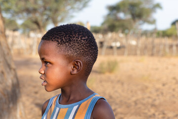 village portrait of african child girl in the Kalahari, yard with the krall in the background