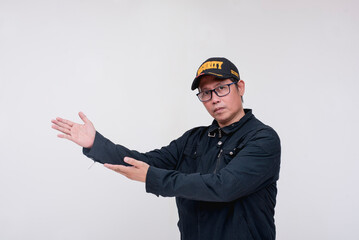 A friendly asian male security guard points to the left with both hands. Doing and handling a...