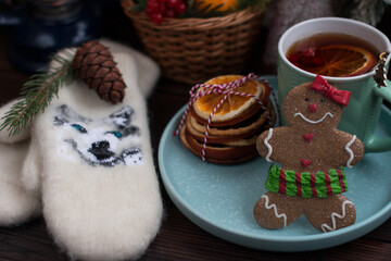 A Christmas tree with toys and a hot cup of orange tea. Warm white mittens and a gingerbread man
