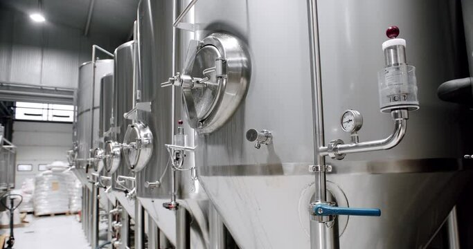 Stainless steel tanks at brewery factory. Vat container with beer brewing. Process of fermentation and maturation. Modern equipment on plant