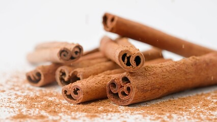 Close up studio shot of food ingredient. A pile of brown dried cinnamon sticks laying on the white background.