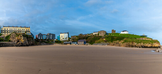 A panorama view from the Castle beach across Castle Hill and South Beach at low tide in Tenby, Wales on a sunny day