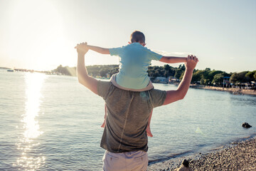 Happy father embracing the son. Father having fun with cute little boy on the beach. Daddy care a...