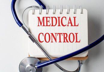 MEDICAL CONTROL word on notebook with medical equipment on background