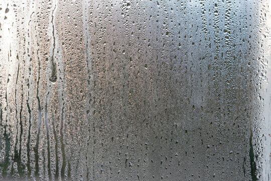 Window glass with steam condensation and drops after or during rain, wet glass as background or texture